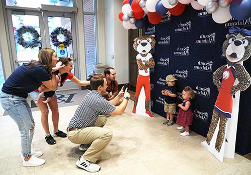 Family taking pictures of their kids in Alumni with cutouts of Southpaw and Ms. Pawla.